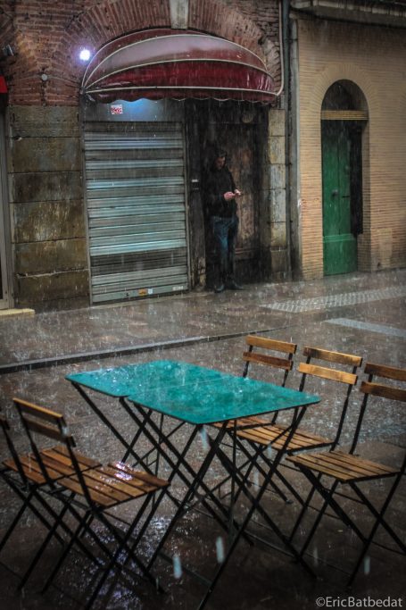 Terrasse sous la pluie Table et chaises mouillées sous la pluie, devant une entrée de café fermée.