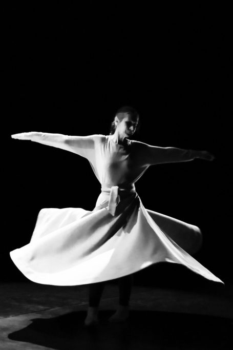 Spectacle de clown Un clown en costume avec moustache, regardant une plume blanche en vol.