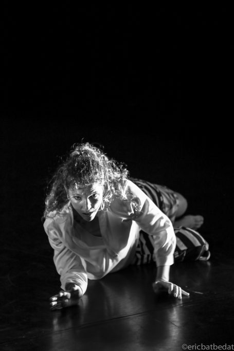 Spectacle - danse Une danseuse au sol, exprimant une intense émotion dans un éclairage sombre.